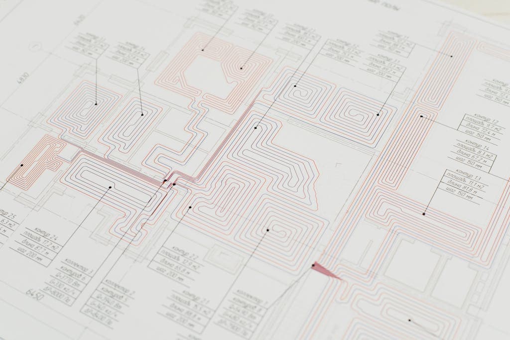 Technical building plan showing a radiant floor heating pipe layout with red and blue circuit lines and labeled zones.
