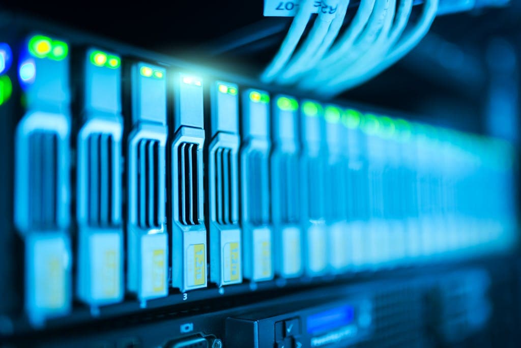 Close-up of network switch ports with Ethernet cables connected and green status lights glowing in a server rack.