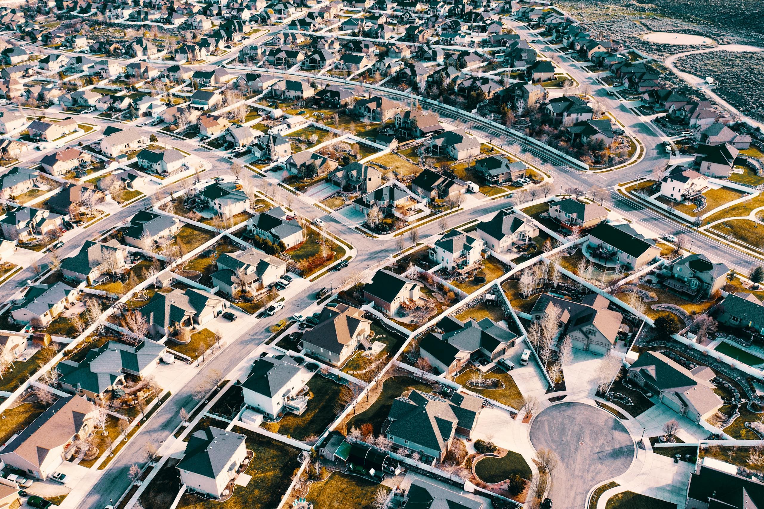 High-angle aerial shot of a suburban neighborhood in Herriman, Utah, showcasing residential architecture and streets.