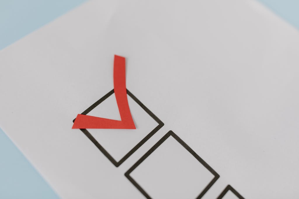 Close-up of a red check mark on a crisp white paper with black boxes, symbolizing completion. Close-up of a red check mark placed in a blank checkbox on a printed checklist form.